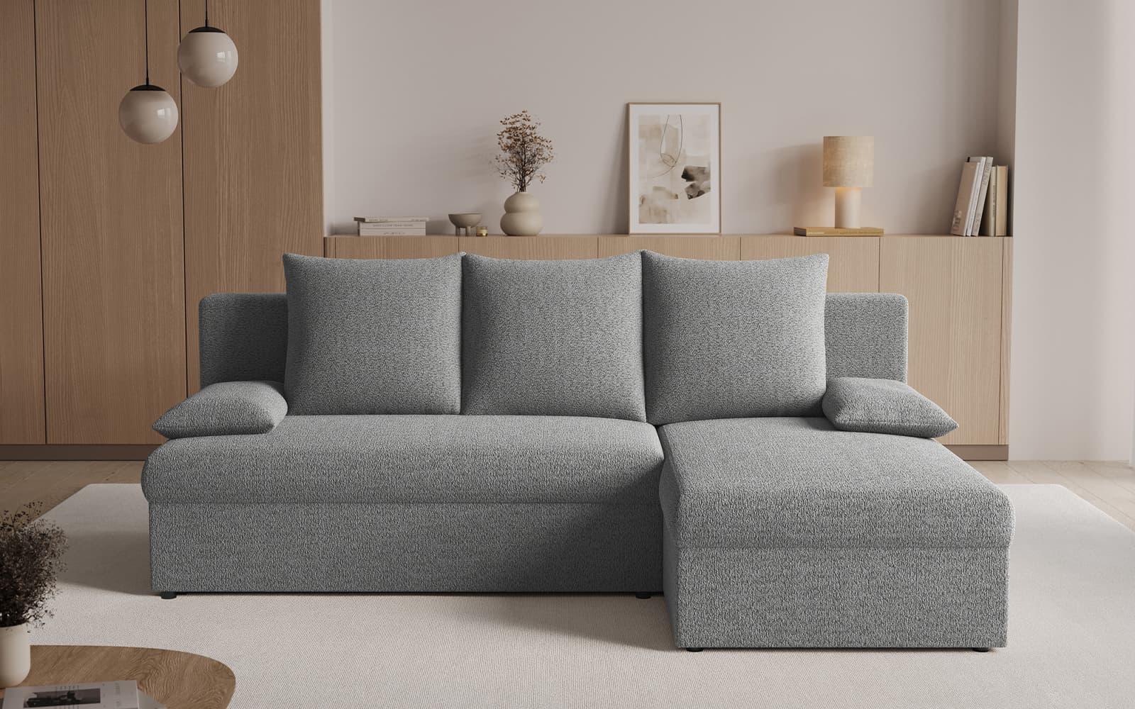 Light gray L-shaped sectional sofa with two matching bolster pillows in a modern living room with wooden cabinets and neutral decor behind.